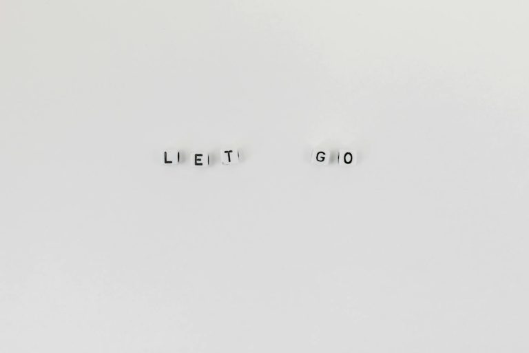 Minimalist composition featuring 'Let Go' spelled with letter dice on a clean white background.