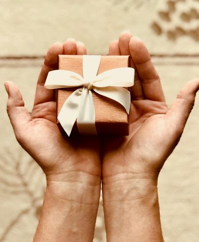 Photo by Kim Stiver Close-up of hands holding a beautifully wrapped gift box with a ribbon, perfect for celebrations and surprises.